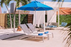 a group of lounge chairs and a blue umbrella at TRYP by Wyndham Aruba in Palm-Eagle Beach