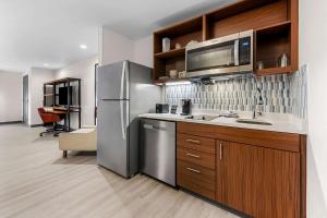 a kitchen with a stainless steel refrigerator and a microwave at Everhome Suites Fayetteville near Fort Bragg in Fayetteville