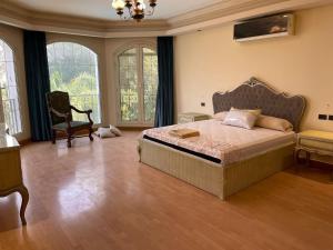 ein Schlafzimmer mit einem Bett und einem Stuhl und Fenstern in der Unterkunft Shorouk Mansion in Madīnat ash Shurūq