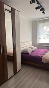 una camera da letto con un letto e un grande specchio di Квартира у Арбата a Shymkent