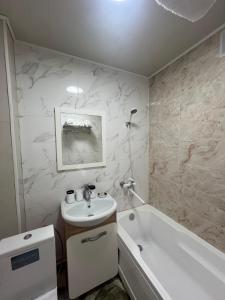 un bagno bianco con lavandino e vasca di Квартира у Арбата a Shymkent