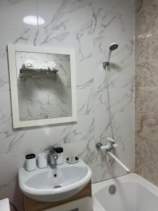 un bagno bianco con lavandino e specchio di Квартира у Арбата a Shymkent Altre 4 foto