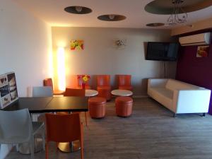 een wachtkamer met oranje stoelen en een tafel en een bank bij HoteI de la Plage Montpellier Sud in Palavas-les-Flots