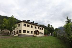 una gran casa blanca con un campo de hierba delante de ella en Casa de Colònies Vall de Boí - Verge Blanca en Llesp