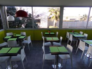 a restaurant with green tables and white chairs at HoteI de la Plage Montpellier Sud in Palavas-les-Flots