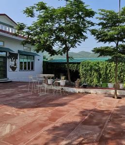 eine Terrasse mit Stühlen, einem Tisch und einem Baum in der Unterkunft The Marker in Tehla