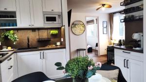 a kitchen with white cabinets and a table with flowers at Panoráma Nyaraló in Tahitótfalu