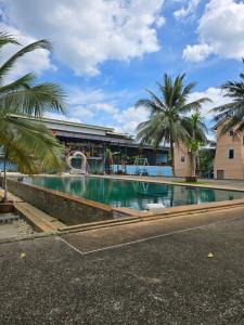 a swimming pool in front of a building with palm trees at Sai Rung Farmstay สายรุ้ง ฟาร์มสเตย์ in Ban Huai Yung