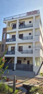 a tall white building with a sign on it at Chiraanya Service Apartment in Chikmagalūr