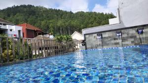 a large swimming pool with blue tiles on the side of a building at Villa kusuma pinus M-59 in Batu