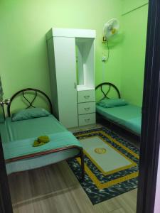 a small room with two beds and a mirror at Aisy Homestay in Kuala Terengganu +1 photo