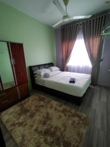 a bedroom with a bed with a window and a rug at Aisy Homestay in Kuala Terengganu