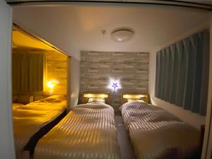 a bedroom with two beds and a cross on the wall at 優富良野 in Furano