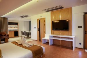 a bedroom with a large bed with a flat screen tv at RAGA - A Boutique Hotel in Belgaum