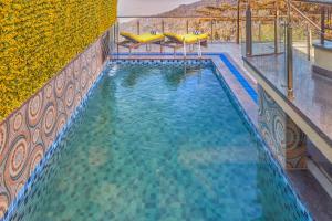a swimming pool with blue water and yellow tables at WelcomHeritage Natraj, Mcleod Ganj in McLeod Ganj