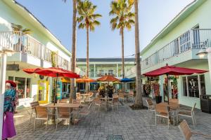 a patio with tables and chairs and palm trees at Sea Woods 115 in New Smyrna Beach