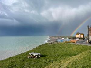 a rainbow over the ocean with a picnic table at L'étoile, Appartement 1 chambre, vue mer- rénové et cosy- tout inclus in Ault