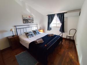 een slaapkamer met een groot bed en een stoel bij casa na aldeia - entre Fundão e Covilhã in Pêro Viseu