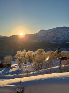 a snowy field with the sun setting in the distance at Private apartments!Oppdal Alpintun, Skisenter-Stølen in Oppdal