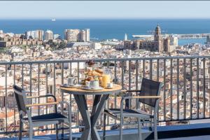 a table and chairs on a balcony with a view of the city at ANSA Beach Apartments - Malaga - Skyline Suite in Málaga