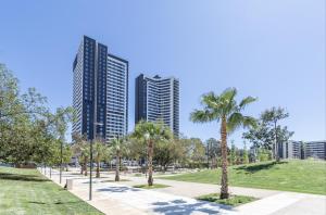 a park with palm trees and tall buildings at ANSA Beach Apartments - Malaga - Skyline Suite in Málaga