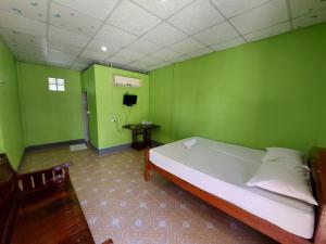 Camera verde con letto e TV di IngTawan Resort อิงตะวัน รีสอร์ท a Sing Buri