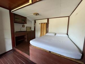 una piccola camera da letto con un letto e una scrivania di IngTawan Resort อิงตะวัน รีสอร์ท a Sing Buri