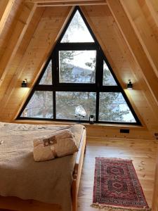 a bedroom with a large window in a cabin at Molika Forest House in Kolašin