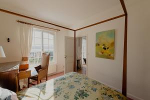 a bedroom with a bed and a desk and a window at La Ronce in Châteauneuf-sur-Loire