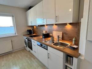a kitchen with white cabinets and a sink at Zentrumsnahe Wohnung, Anviolhomes in Hannover +14 photos