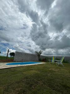 two chairs and a swimming pool under a cloudy sky at Cantinho da Rasa in Cabo Frio