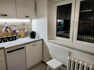 a kitchen with white cabinets and a chair and a window at Amelia1 in Toruń +9 photos