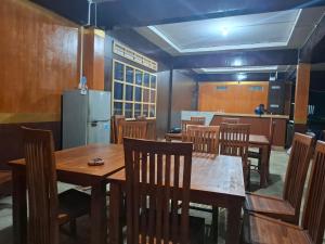 a dining room with wooden tables and chairs and a refrigerator at Pondok Roomi Villa in Sembalun Lawang +50 photos