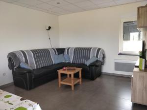 un soggiorno con un divano nero e un tavolo di Maisonjoske a Beaulieu