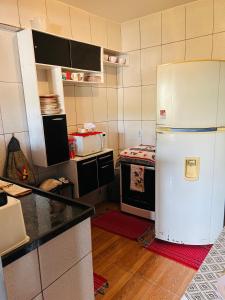 Il comprend une cuisine équipée d'un réfrigérateur blanc et d'une cuisinière. dans l'établissement Cantinho Oliveiras, à Cabo Frio