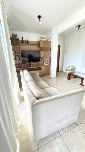 a living room with a white couch and a tv at Pousada Altos dos Ingleses II in Florianópolis +63 photos