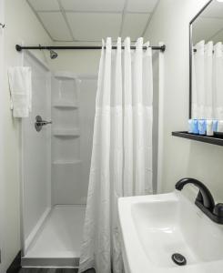 a white bathroom with a shower and a sink at River City Inn in Parsons