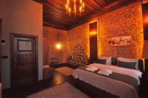 een slaapkamer met een bed en een bakstenen muur bij Mihman Konak Hotel in Kars +30 foto's