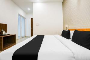 a bedroom with a large white bed with black pillows at The Grand Blue Hotel in Greater Noida