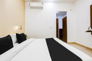 a bedroom with a large white bed with black pillows at The Grand Blue Hotel in Greater Noida