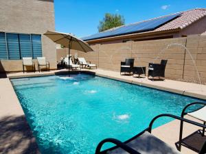 una gran piscina con sillas y sombrilla en 4 Season Spa Heated Dream Pool Jacuzzi Sauna, en Casa Grande