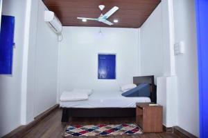 a small room with a bed with a ceiling fan at Blue Bell Homestay in Udupi
