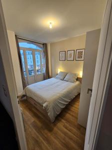 a bedroom with a bed and a large window at L'authentique - Appartement 4 in Loudéac
