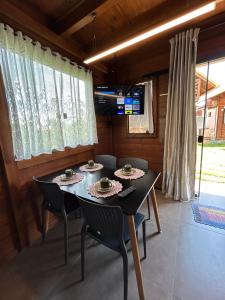 a dining room with a black table and chairs at Pousada Chalé Flor de Hibisco 2 in Penha