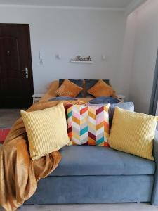 - un canapé bleu avec des oreillers colorés dans l'établissement Appartment Alicja, à Darłowo 7 autres photos