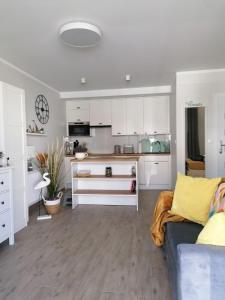 une cuisine avec des placards blancs et un canapé bleu dans l'établissement Appartment Alicja, à Darłowo