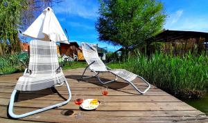 two lawn chairs sitting on a wooden deck with wine glasses at Zöld Orom Vendégház in Békésszentandrás