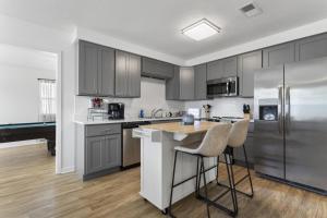 a kitchen with gray cabinets and a kitchen island with bar stools at Coastal Retreat by the Beach in Long Beach