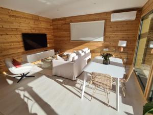 a living room with white furniture and a flat screen tv at Le Cottage des Cerisiers in Saint-Paul-en-Cornillon