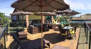 a deck with a table and chairs and umbrellas at Pousada Anjos - à 2 quadras do mar in Matinhos
